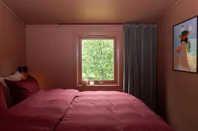 a bedroom with a red bed and a window at Lite hus 40 minutter unna Bergen in Bjørkheim