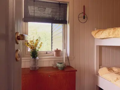 a bedroom with a window and a wooden table with flowers at Lite hus 40 minutter unna Bergen in Bjørkheim
