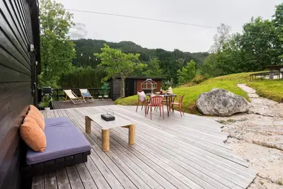 a wooden deck with a table and chairs on it at Lite hus 40 minutter unna Bergen in Bjørkheim