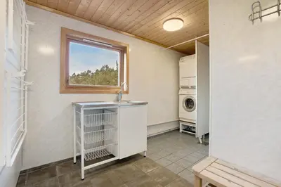 a laundry room with a sink and a window at Gunnarhytta, Valevåg in Valevåg