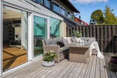 a patio with a couch and a table on a deck at 7 min to Ski Championship, Glass front house, Terrace in Trondheim