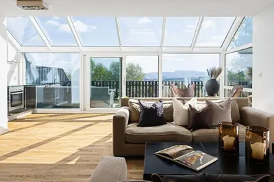 a living room with a couch and a large window at 7 min to Ski Championship, Glass front house, Terrace in Trondheim