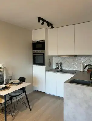 a kitchen with white cabinets and a table with chairs at Plaza Havstad in Trondheim