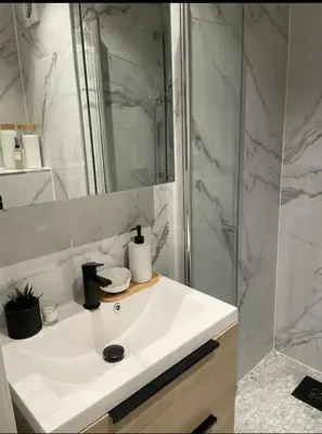a bathroom with a white sink and a shower at Plaza Havstad in Trondheim