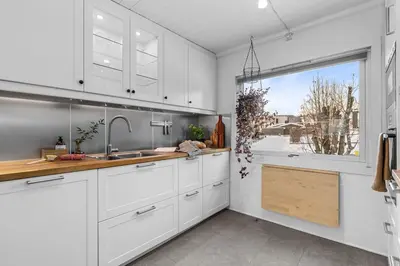 a kitchen with white cabinets and a large window at Villekulla - Koselig hus med jazzuci i Hamar in Hamar