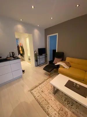 a living room with a yellow couch and a table at Moderne leilighet nær sentrum in Ålesund