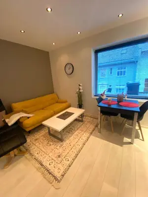 a living room with a yellow couch and a table at Moderne leilighet nær sentrum in Ålesund