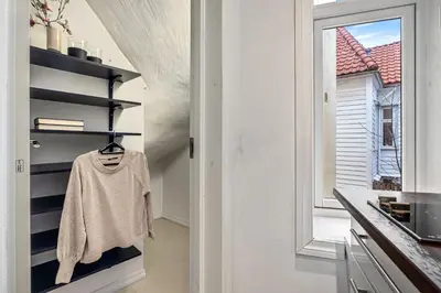 a kitchen with white walls and a shelf with a sweater at Charming apartment in Sandviken in Bergen