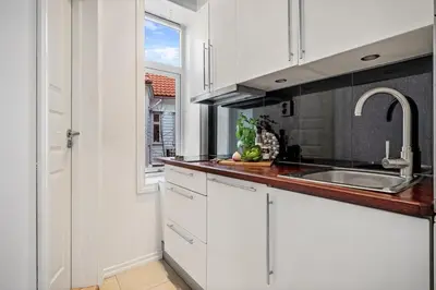 a kitchen with white cabinets and a sink and a window at Charming apartment in Sandviken in Bergen