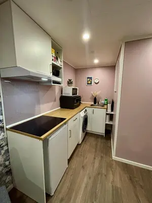 a small kitchen with white cabinets and a sink at Cozy Apartment in Ålesund