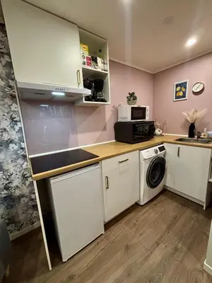 a kitchen with white cabinets and a washer and dryer at Cozy Apartment in Ålesund