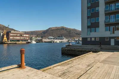 a dock next to a building next to a body of water at Modern Apartment with Rooftop Terrace and Stunning Views in Bergen