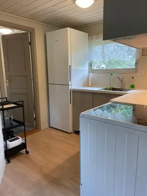 a kitchen with a white refrigerator and a sink at Hytte ved sjøen med båtutleige in Kvalsvik