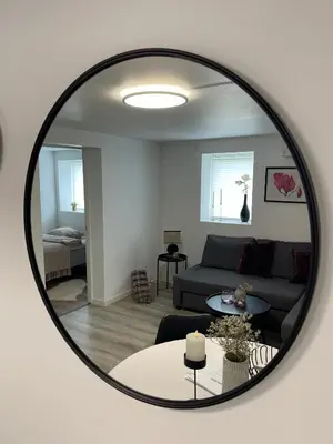a mirror reflecting a living room with a couch at Charming Modern Apartment Close to Moa & Ålesund in Ålesund