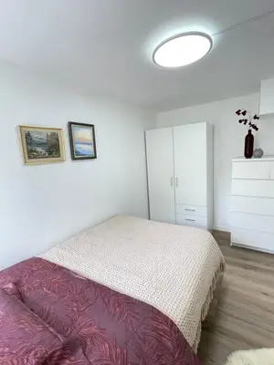 a white bedroom with a bed and a white cabinet at Charming Modern Apartment Close to Moa & Ålesund in Ålesund