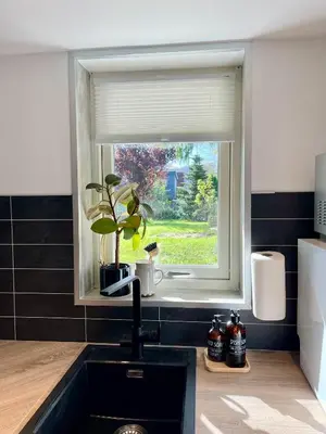 a kitchen sink with a window and a plant at Charming Modern Apartment Close to Moa & Ålesund in Ålesund