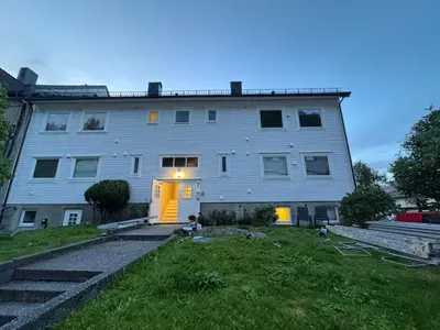 a large white building with a yellow door at Alesund bedroom with shared shower in Ålesund