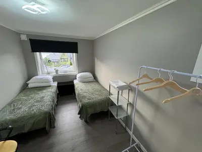 a small room with two beds and a window at Alesund bedroom with shared shower in Ålesund