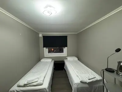 two beds in a small room with a window at Alesund bedroom with shared shower in Ålesund