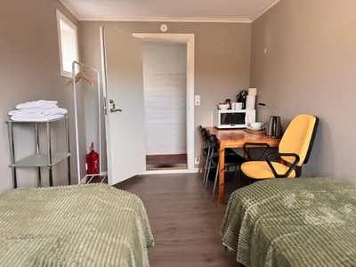 a room with a desk and a table with a microwave at Alesund bedroom with shared shower in Ålesund
