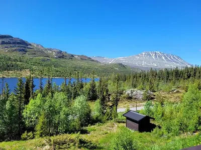 a small cabin in a field with a lake and mountains at Gaustablikk, 3 soverom, fri utsikt til fjell og innsjø in Gaustablikk