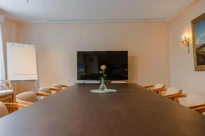 a conference room with a large wooden table and a vase with a flower at Orkla Gjestebolig in Løkken