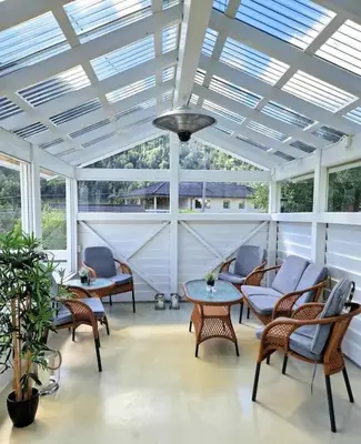 a screened porch with chairs and tables and a ceiling at Fjellhagen - Geirangerfjord view in Hellesylt