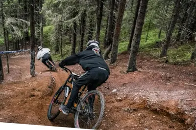 two people riding bikes on a dirt trail in the woods at Skistadion Hafjell in Hafjell