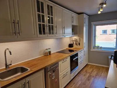 a kitchen with white cabinets and a sink and a window at Central and cosy apartment in Trondheim, Free parkingspot in Trondheim