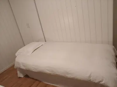 a white bed in a corner of a room at Trysil sentrum leilighet in Trysil