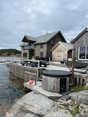 a house with a dock and a boat on the water at Amundøya Boathouse in Vadstensvik