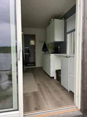 a kitchen with white cabinets and a large glass door at Amundøya Boathouse in Vadstensvik