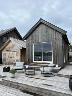 a building with a deck with two chairs and a table at Amundøya Boathouse in Vadstensvik