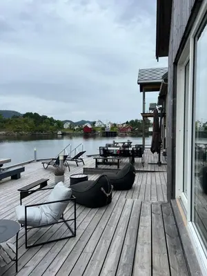 a wooden deck with chairs and tables on the water at Amundøya Boathouse in Vadstensvik