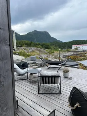 a deck with a hammock and a table and chairs at Amundøya Boathouse in Vadstensvik