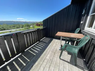 a wooden deck with a table and a green chair at Cozy 3-Bedroom Apartment Near Beitostølen Ski in Beitostøl