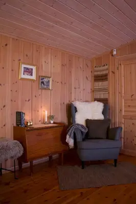 a living room with a chair and a piano at Koselig familiehytte på Rømåsen in Ringsaker