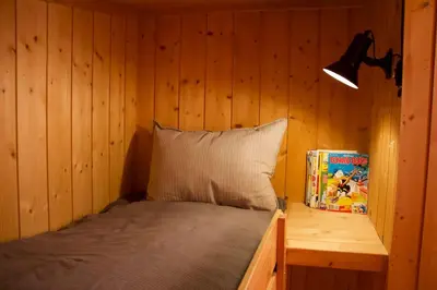 a bed in a room with a wooden wall at Koselig familiehytte på Rømåsen in Ringsaker