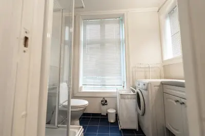 a white bathroom with a toilet and a window at Leilighet i Ålesund Sentrum in Ålesund