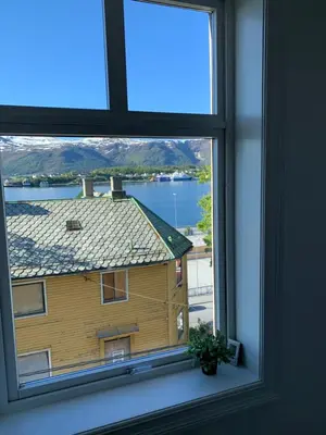 a window with a view of a house and a lake at Leilighet i Ålesund Sentrum in Ålesund