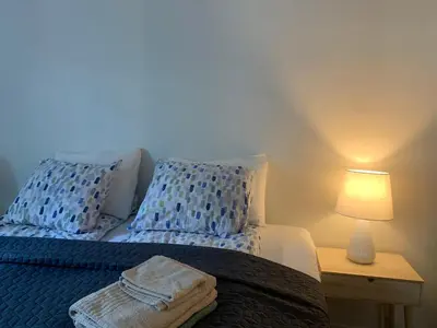 a bedroom with a bed with blue pillows and a lamp at Moderne og fullt utstyrt 3-rom hageleilighet sentrum nær in Bergen