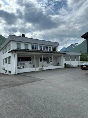 a white building with a car parked in a parking lot at Damehuset in Sæbø