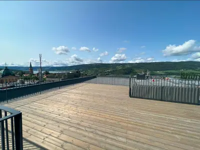 a wooden deck with a fence and mountains in the background at midt i Lillehammer in Lillehammer