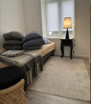 a bedroom with a bed with a lamp and a window at Downtown free parking cozy apartment in Ålesund