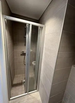 a shower with a glass door in a bathroom at Downtown free parking cozy apartment in Ålesund
