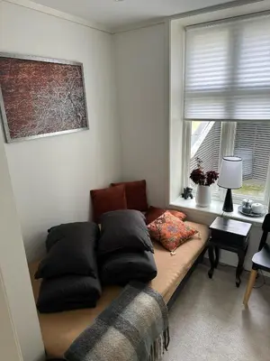 a room with a couch with pillows and a window at Downtown free parking cozy apartment in Ålesund