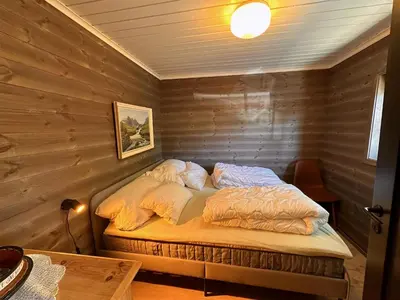 a bed in a room with a wooden wall at Modern Cozy Cabin Near Langsua National Park in Heggenes