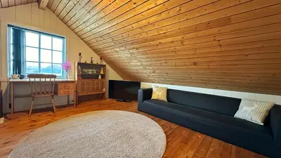 a living room with a blue couch and a wooden ceiling at Cozy Cabin in Volda
