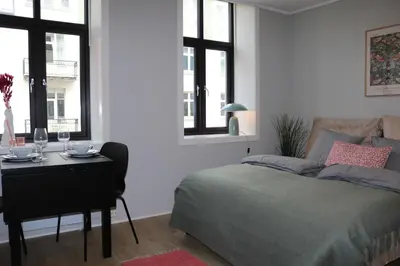 a bedroom with a bed and a desk and windows at One-bedroom apartment close to NTNU and St Olavs in Trondheim