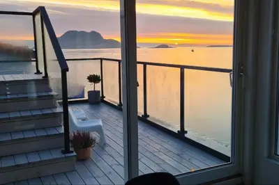a balcony with a view of the ocean and a sunset at Villa with a view in Ålesund